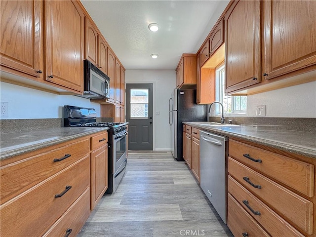 kitchen with stainless steel appliances, dark countertops, light wood-type flooring, plenty of natural light, and recessed lighting