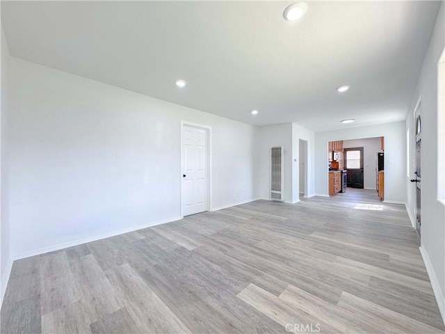 spare room featuring recessed lighting, light wood-type flooring, a heating unit, and baseboards