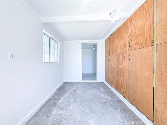 unfurnished bedroom with unfinished concrete floors, baseboards, and crown molding