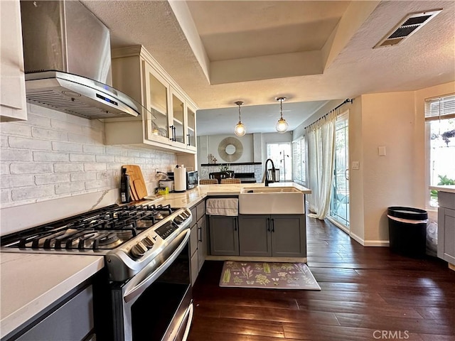 1512 W Sunnyview Dr, Rialto, CA 92377 - kitchen with wall chimney range hood, stainless steel gas stove, a sink, a peninsula, and gray cabinetry
