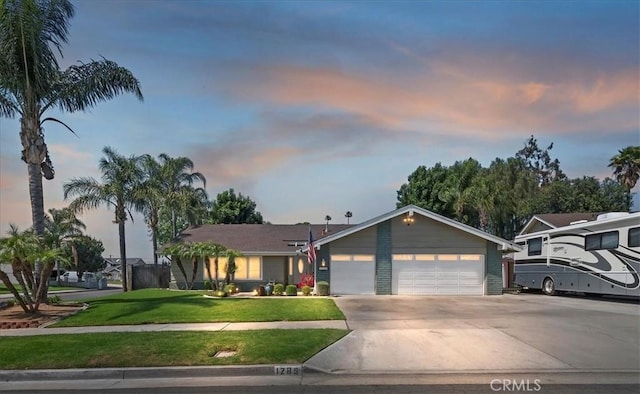 view of front of home with driveway, an attached garage, and a yard