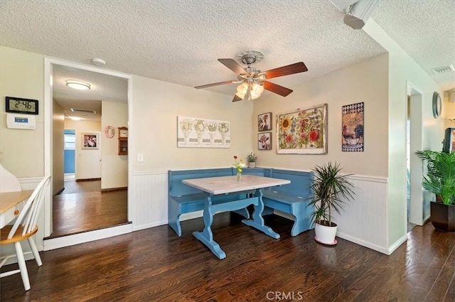 dining space featuring a textured ceiling, wood finished floors, wainscoting, and ceiling fan