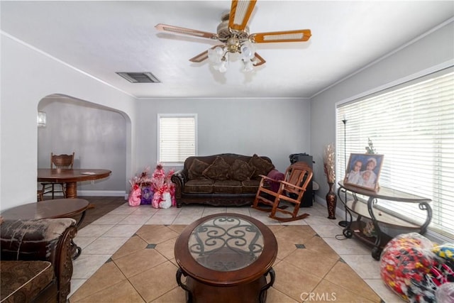 living room with arched walkways, light tile patterned flooring, ceiling fan, and baseboards