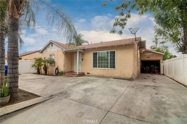 view of front facade featuring stucco siding, fence, a garage, and concrete driveway