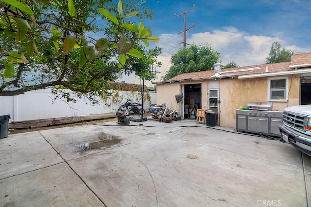view of patio featuring fence and a grill