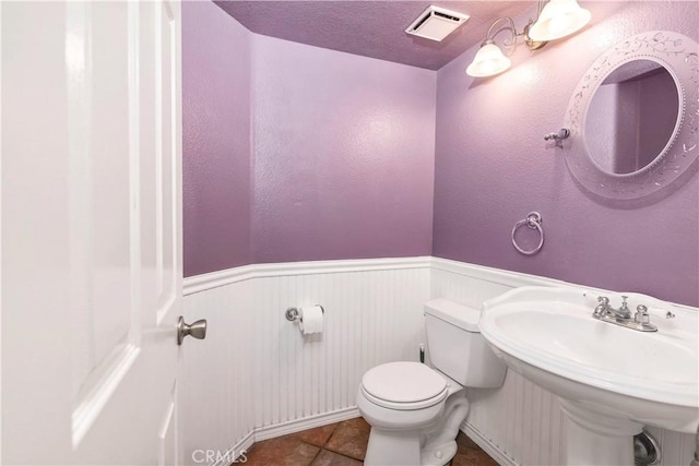 half bathroom with a wainscoted wall and toilet