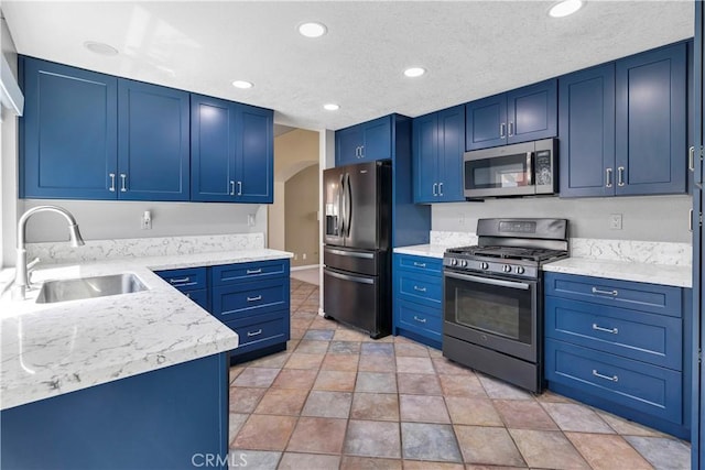 kitchen with stainless steel appliances, a sink, blue cabinets, recessed lighting, and stone finish flooring
