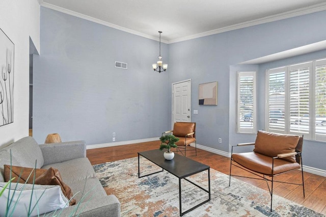 living area with a chandelier, wood finished floors, baseboards, and crown molding