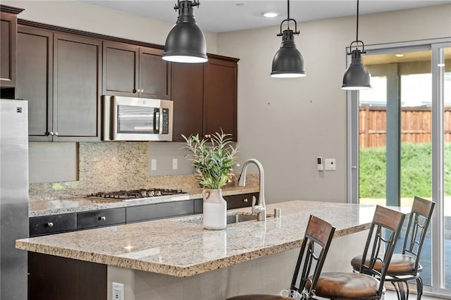 27490 Grand Teton Ct, Menifee, CA 92585 - kitchen featuring stainless steel appliances, backsplash, dark brown cabinets, a sink, and pendant lighting