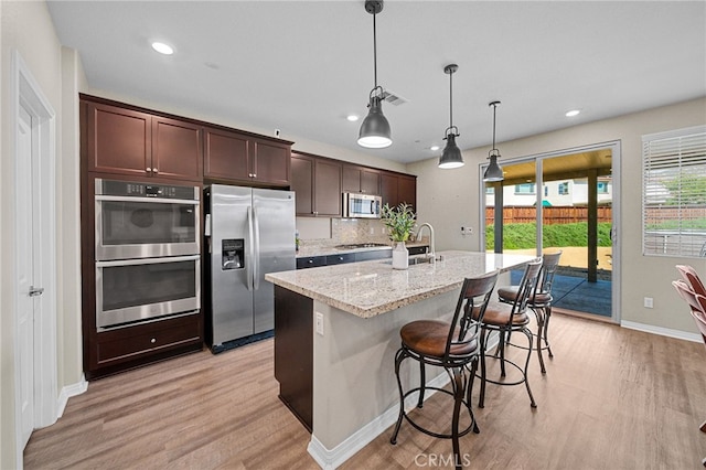27490 Grand Teton Ct, Menifee, CA 92585 - kitchen featuring stainless steel appliances, light wood-type flooring, baseboards, light stone counters, and recessed lighting