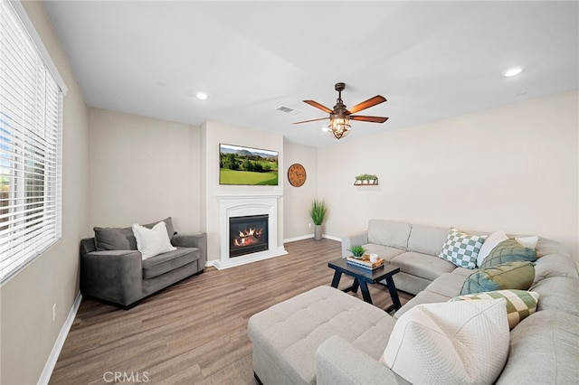 27490 Grand Teton Ct, Menifee, CA 92585 - living area with baseboards, wood finished floors, a glass covered fireplace, recessed lighting, and ceiling fan