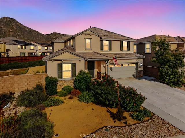 traditional-style home featuring stone siding, stucco siding, and an attached garage
