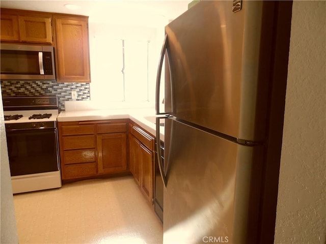 1806 Rory Ln Unit 9, Simi Valley, CA 93063 - kitchen featuring stainless steel appliances, brown cabinetry, light countertops, decorative backsplash, and a textured wall