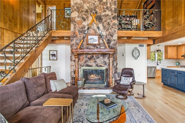 28834 Zion Dr, Lake Arrowhead, CA 92352 - living area with light wood finished floors, a high ceiling, stairs, a stone fireplace, and wood walls