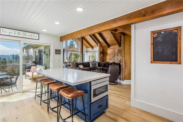 28834 Zion Dr, Lake Arrowhead, CA 92352 - kitchen with blue cabinets, wooden ceiling, stainless steel microwave, light wood-style floors, and plenty of natural light