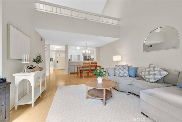 7402 Yellowtail Dr Unit 204, Huntington Beach, CA 92648 - living area featuring light wood-style floors, a chandelier, and a high ceiling