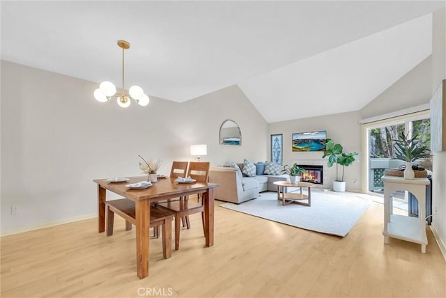 7402 Yellowtail Dr Unit 204, Huntington Beach, CA 92648 - dining space with light wood finished floors, a chandelier, a glass covered fireplace, and lofted ceiling