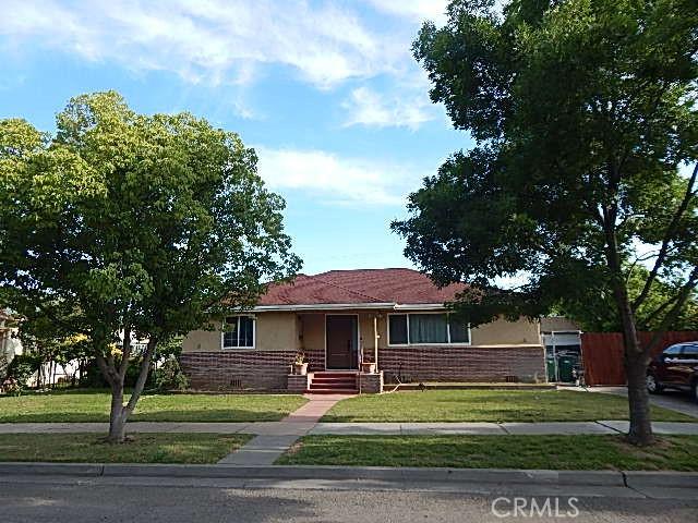 1427 Yolo St, Corning, CA 96021 - view of front of home featuring stucco siding, a front lawn, and brick siding