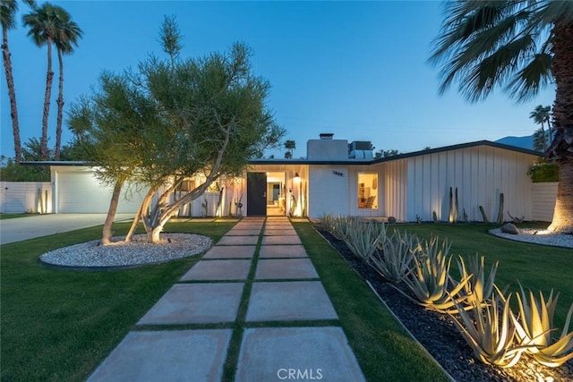 view of front of property featuring concrete driveway, a front yard, a chimney, board and batten siding, and an attached garage