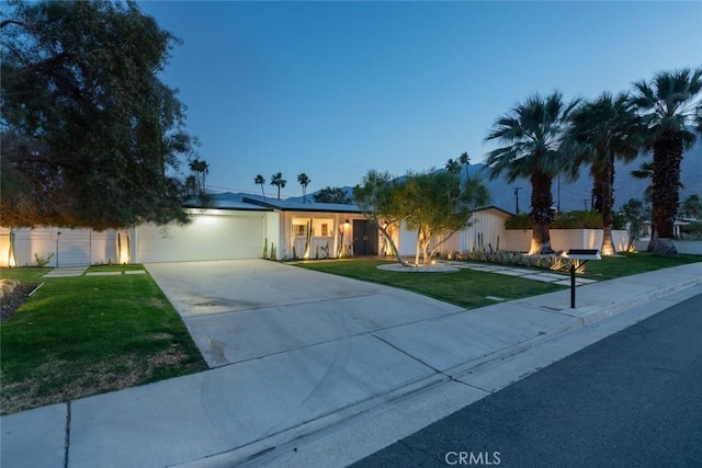 ranch-style house with concrete driveway, a front lawn, and an attached garage