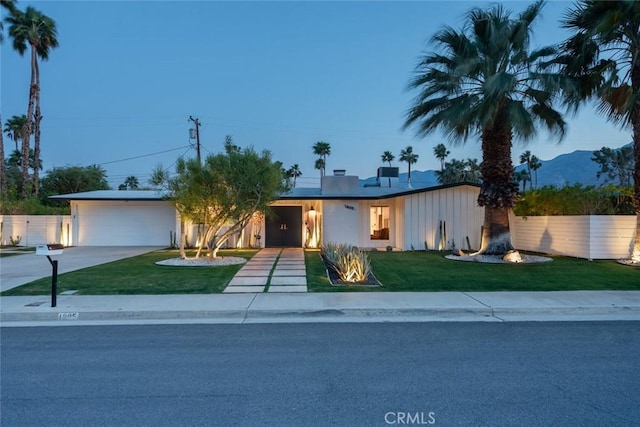 view of front of property with concrete driveway, a front lawn, and a garage