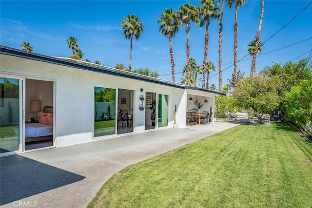 rear view of house with a patio, stucco siding, and a yard