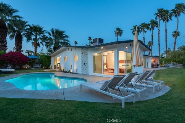 back of property with a patio, stucco siding, a lawn, and an outdoor pool
