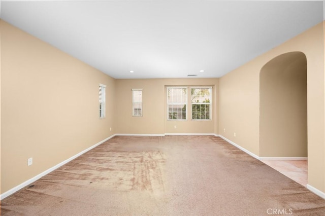 empty room with carpet flooring, baseboards, arched walkways, and recessed lighting