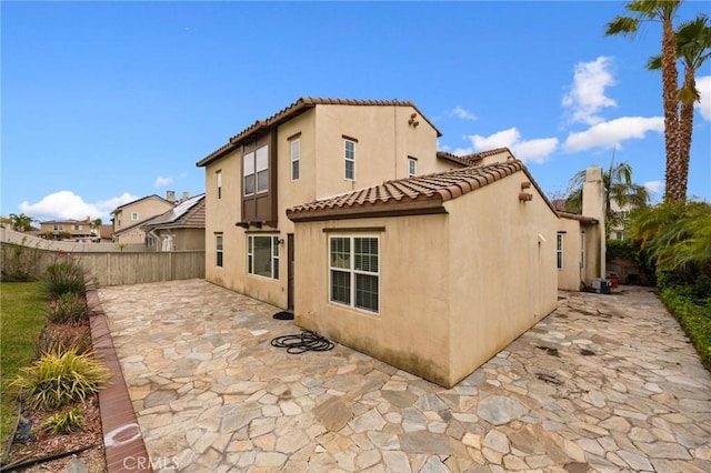 back of house with stucco siding, a tiled roof, a patio, and a fenced backyard