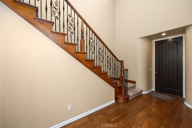 entrance foyer featuring hardwood / wood-style floors, baseboards, stairs, and a towering ceiling