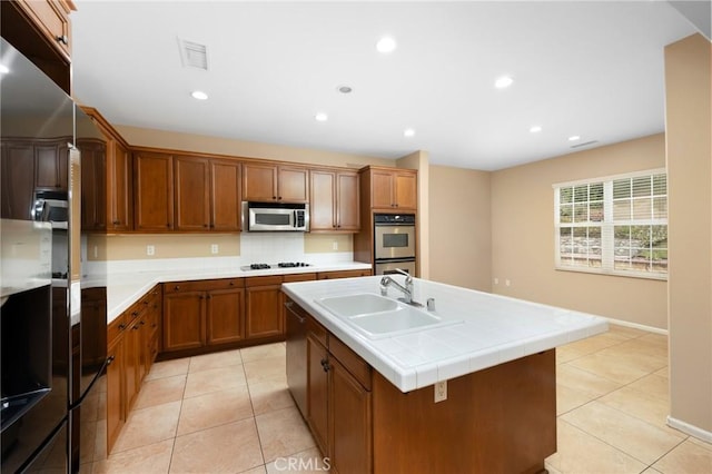 kitchen with appliances with stainless steel finishes, a sink, brown cabinetry, recessed lighting, and light tile patterned flooring