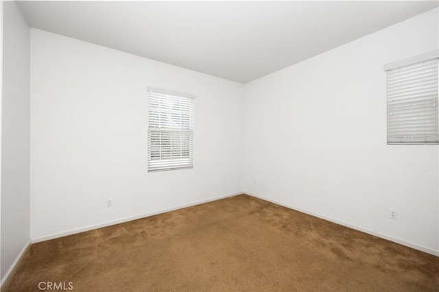 unfurnished room with carpet floors and baseboards