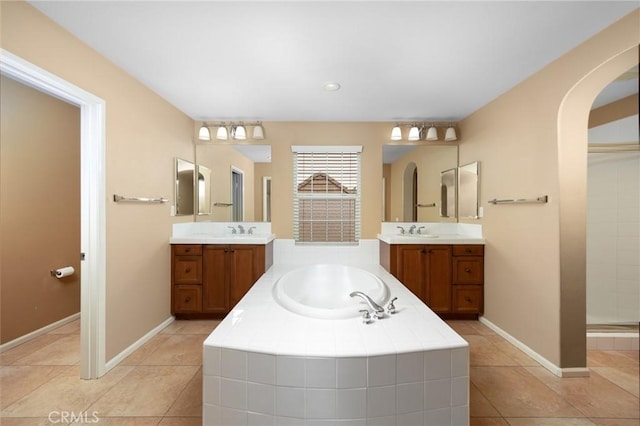 full bath featuring a garden tub, tile patterned flooring, and two vanities