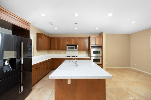 kitchen featuring stainless steel appliances, a sink, a center island with sink, light tile patterned floors, and recessed lighting