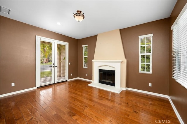 unfurnished living room with baseboards, wood finished floors, and healthy amount of natural light