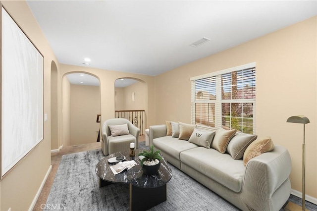 living area featuring arched walkways, baseboards, carpet floors, and recessed lighting