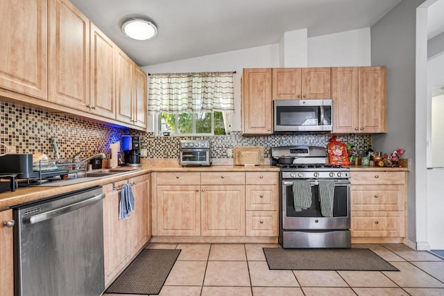 2045 Cardinal Dr, San Diego, CA 92123 - kitchen with stainless steel appliances, light brown cabinetry, vaulted ceiling, tasteful backsplash, and light tile patterned flooring