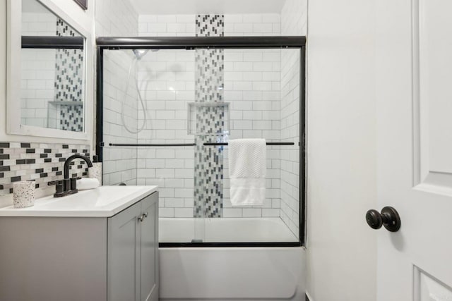 bathroom featuring enclosed tub / shower combo, vanity, and decorative backsplash