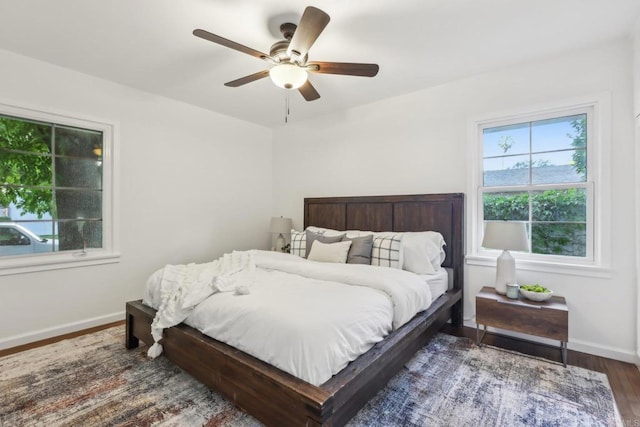 bedroom featuring multiple windows, wood finished floors, baseboards, and a ceiling fan