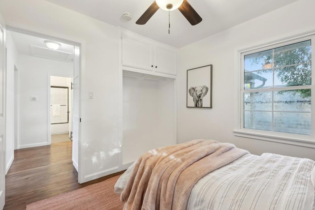 bedroom featuring attic access, wood finished floors, a closet, baseboards, and ceiling fan