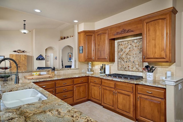 2021 Willow Glen Rd, Fallbrook, CA 92028 - kitchen with a sink, stainless steel gas stovetop, brown cabinets, and light stone countertops