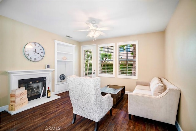 7 Honeydew, Irvine, CA 92603 - sitting room featuring ceiling fan, dark wood-type flooring, a glass covered fireplace, baseboards, and built in shelves