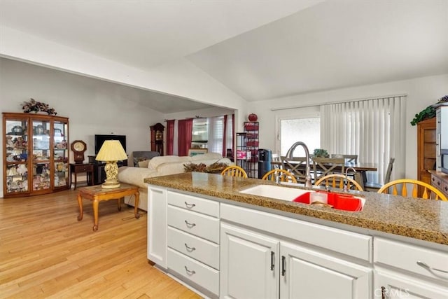 2522 S Calaveras Pl, Ontario, CA 91761 - kitchen with a sink, vaulted ceiling, light wood-style flooring, white cabinets, and light stone countertops