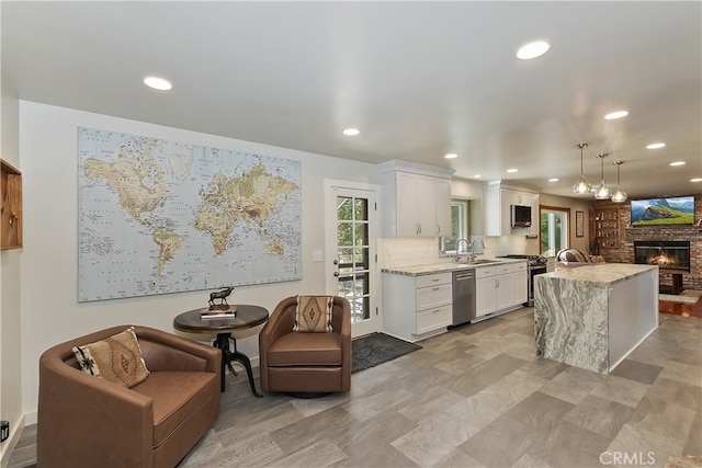 27513 St Bernard Ln, Lake Arrowhead, CA 92352 - kitchen with stainless steel appliances, a glass covered fireplace, white cabinets, a sink, and recessed lighting
