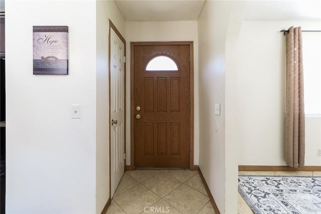 doorway to outside with baseboards and light tile patterned flooring