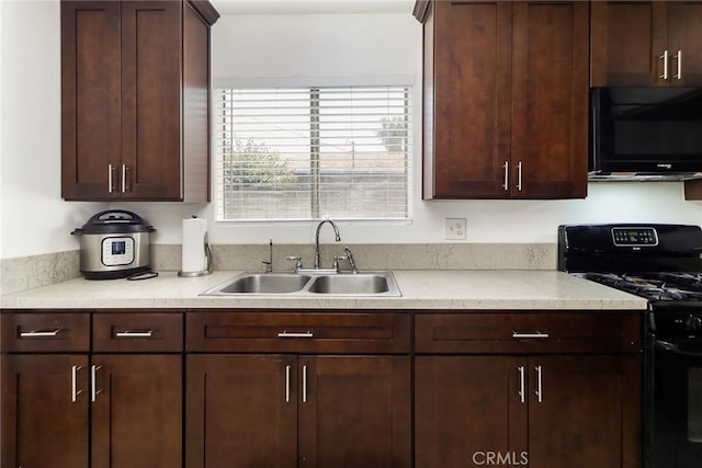 kitchen with black appliances, a sink, light countertops, and dark brown cabinets