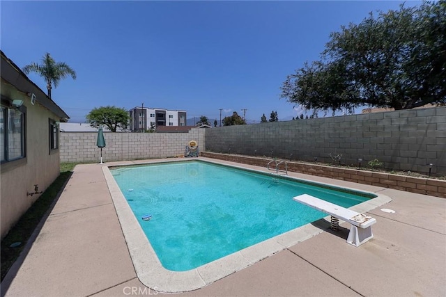 view of swimming pool with a fenced backyard, a patio area, and a diving board