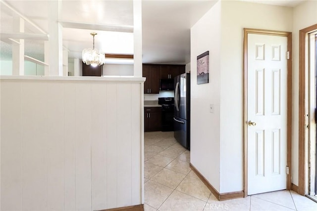 hallway featuring light tile patterned floors, a chandelier, and baseboards