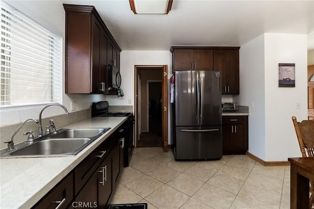 kitchen with freestanding refrigerator, a sink, gas range oven, black microwave, and light countertops
