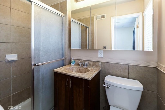 full bath featuring a shower stall, tile walls, toilet, and vanity